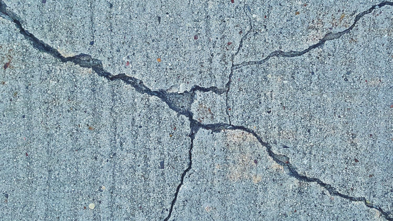 Concrete surface with multiple intersecting cracks extending across the foundation.